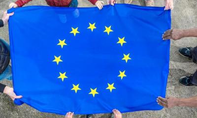 Et EU flag holdes af en gruppe på fem mennesker