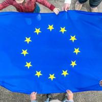 Et EU flag holdes af en gruppe på fem mennesker